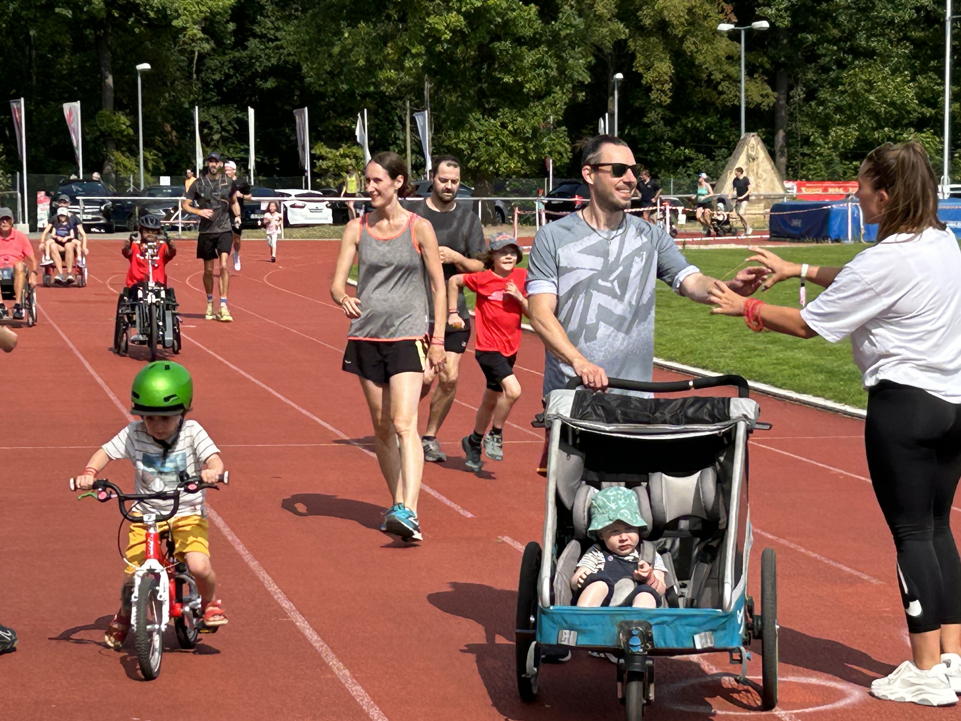 Menschen laufen zu Fuß oder fahren im Rollstuhl über die Tartanbahn beim MTV Spendenlauf.