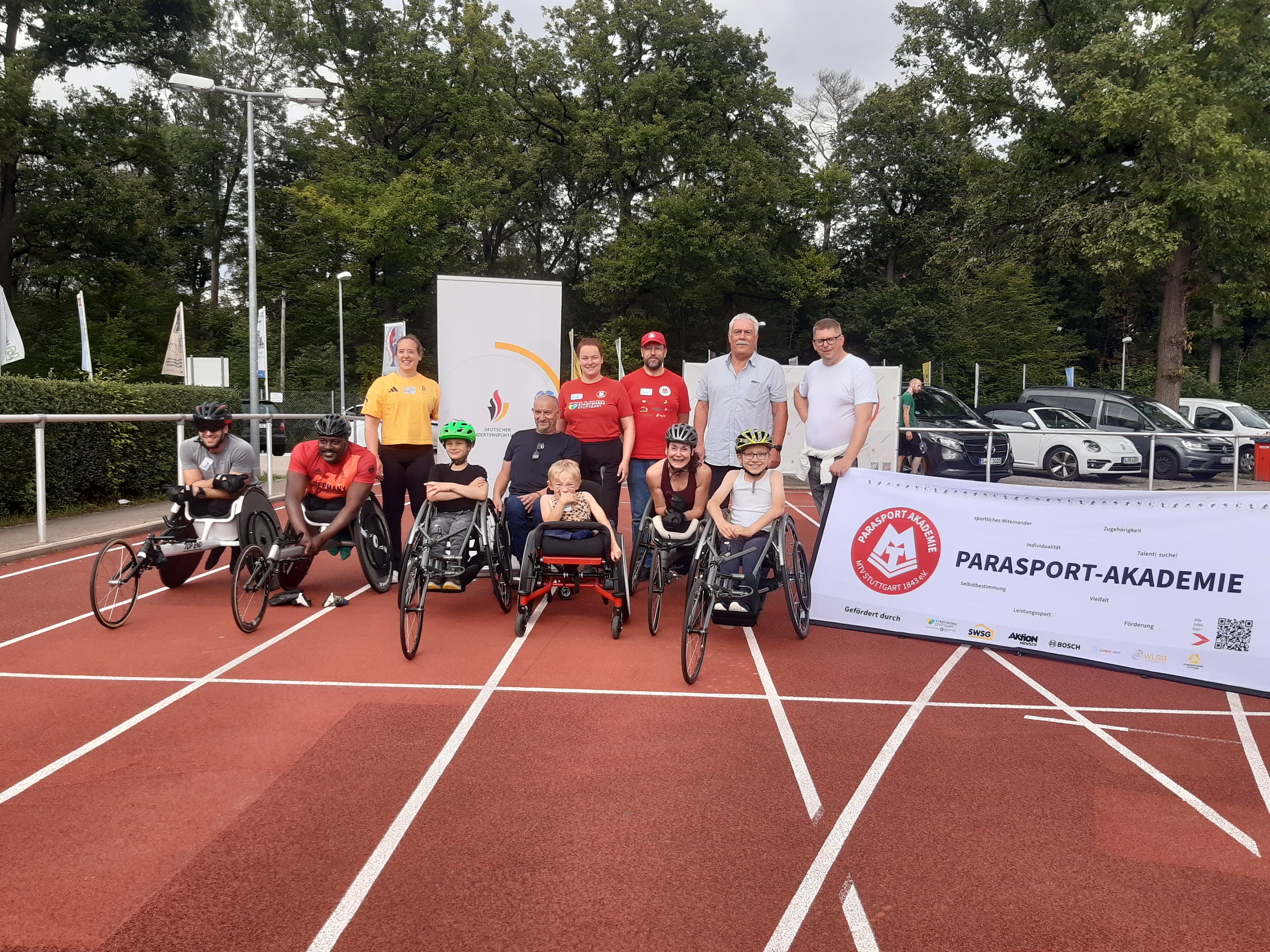 Alle Teilnehmer:innen und Trainer sowie Organisator:innen stehen auf der Tartanbahn für ein Gruppenbild