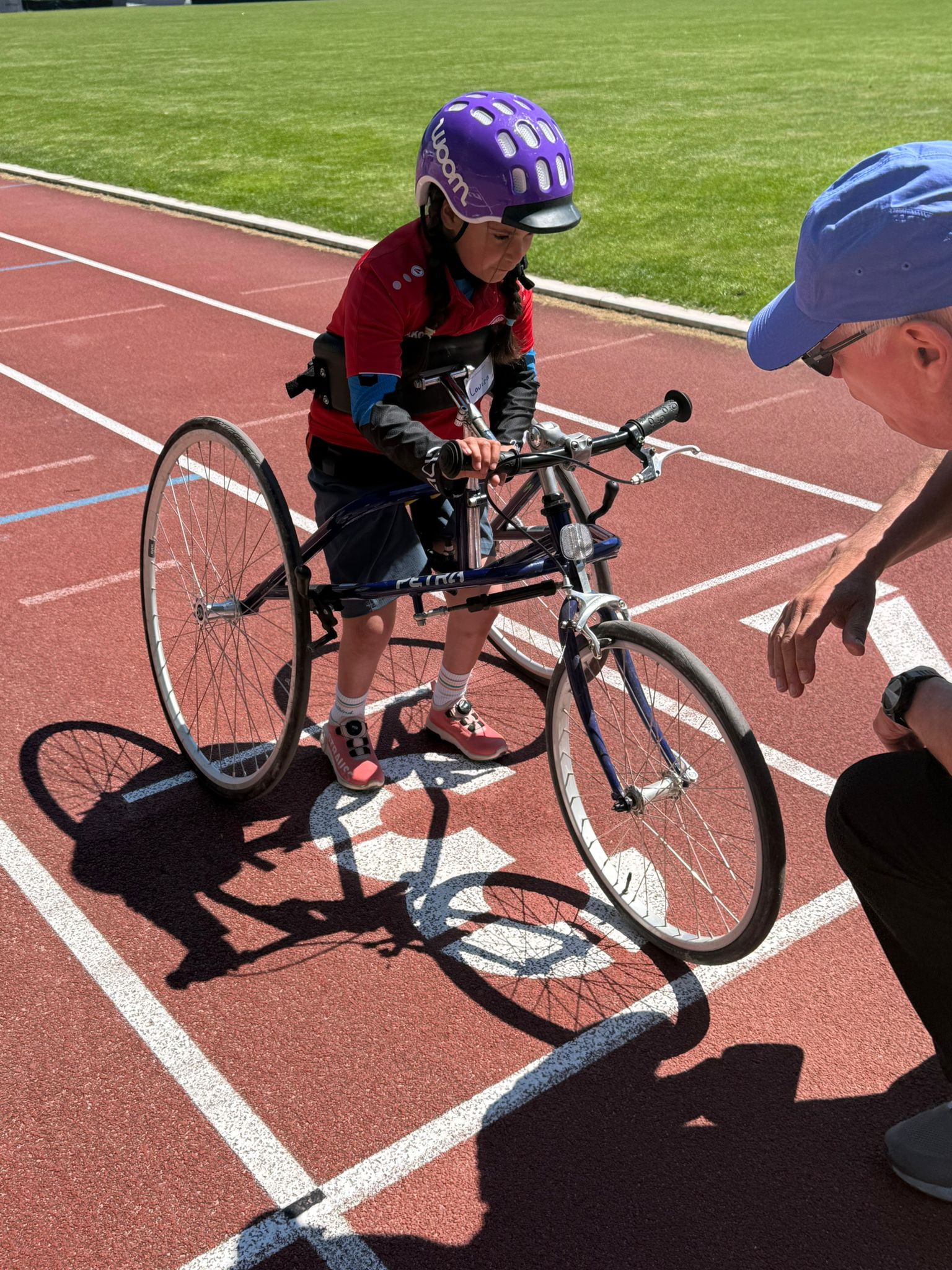 Der Trainer korrigiert noch etwas am Frame eines kleinen Mädchens im Wheelers Trikot