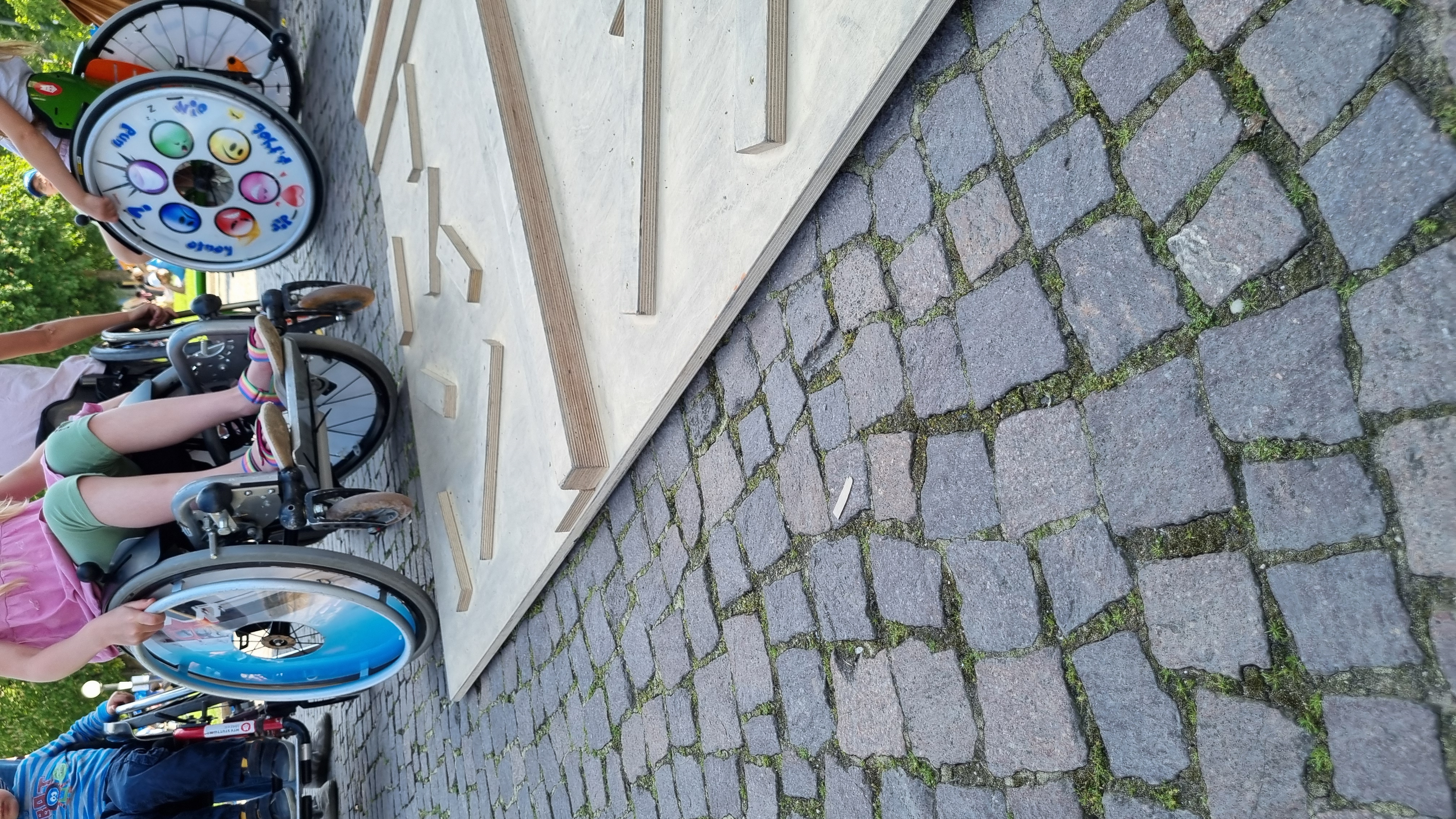 Die Sportler auf ihren Running Frames stehen in einer Reihe und lächeln. Dahinter die Trainer:innen